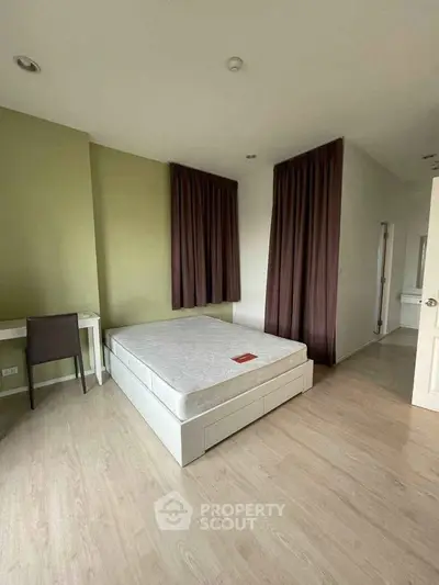 Spacious bedroom with modern decor and natural light, featuring a comfortable bed and study area.