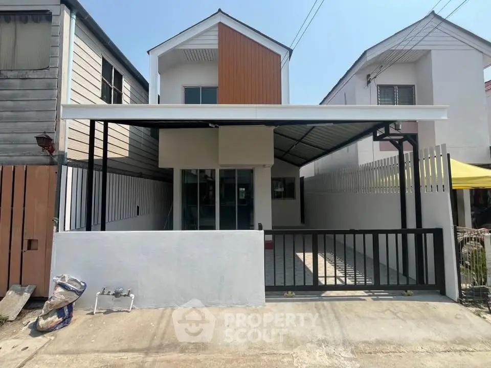 Modern two-story house with carport and gated entrance in a suburban neighborhood.