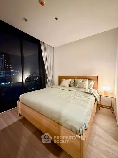 Modern bedroom with city view, featuring a cozy bed and ambient lighting for a serene atmosphere.