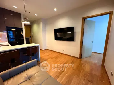 Modern living room with sleek TV setup and stylish kitchen bar area.