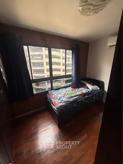 Cozy bedroom with city view, featuring a single bed and large window for natural light.
