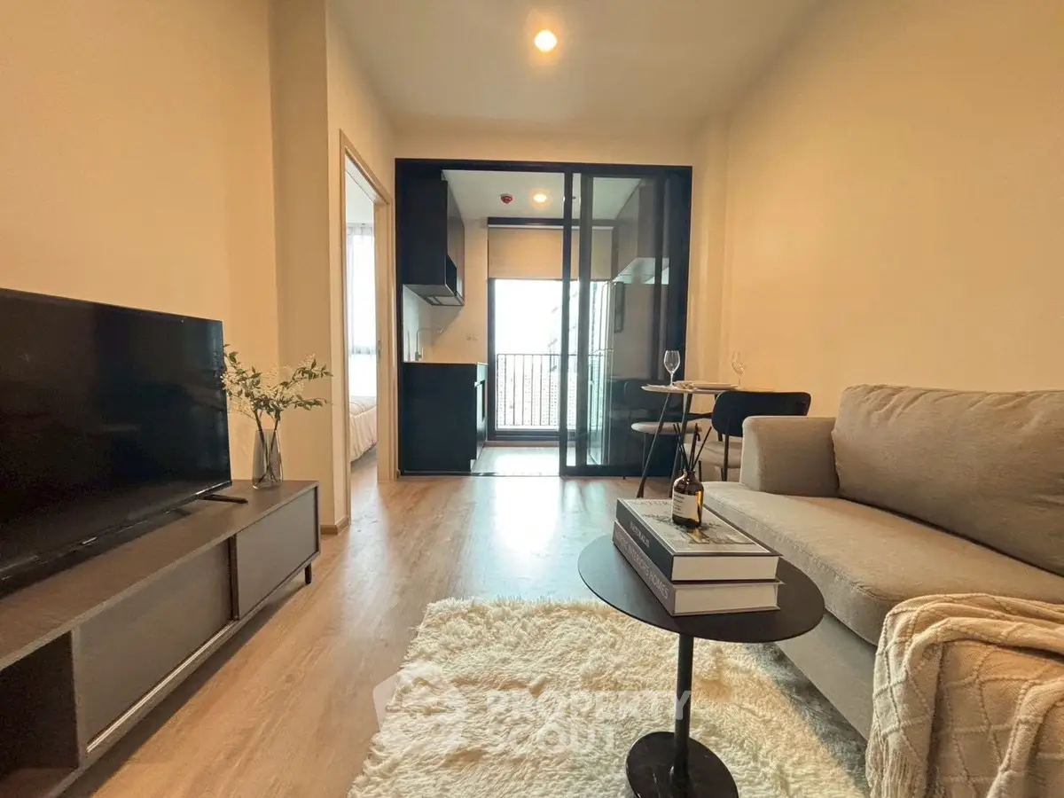 Modern living room with cozy sofa, TV, and open kitchen layout in stylish apartment.