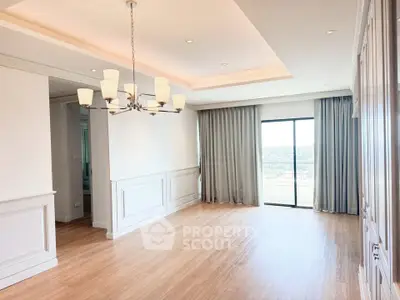 Spacious living room with elegant chandelier and large window offering stunning views.