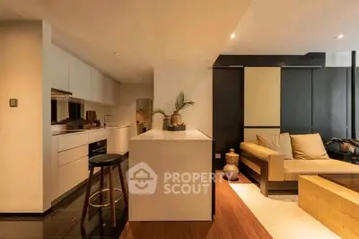 Modern open-layout kitchen and living room with stylish decor and warm lighting.