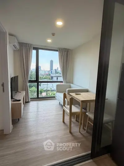 Modern living room with city view, featuring cozy seating and dining area, perfect for urban living.