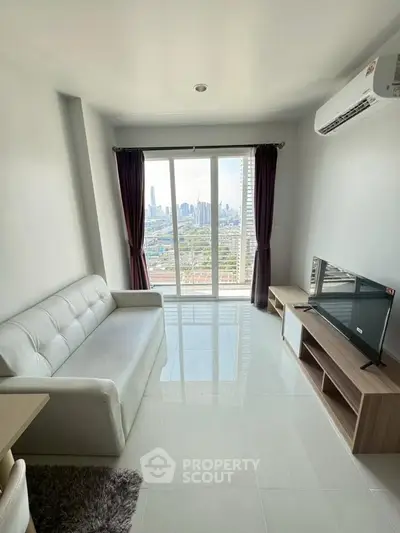 Modern living room with city view, featuring sleek white sofa and entertainment unit.