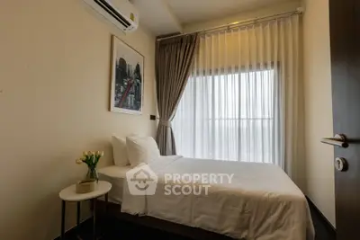 Cozy bedroom with modern decor and large window offering natural light.
