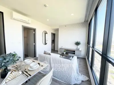 Modern living room with panoramic windows and stylish decor in a high-rise apartment.