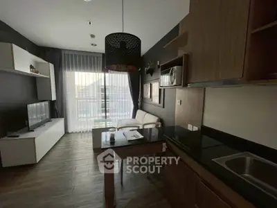 Modern living room with sleek kitchen, stylish decor, and natural light from large windows.