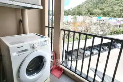 Balcony with washing machine and scenic view of parking area and greenery.