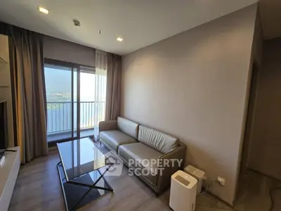 Modern living room with sleek sofa and glass coffee table, offering a stunning city view from the balcony.