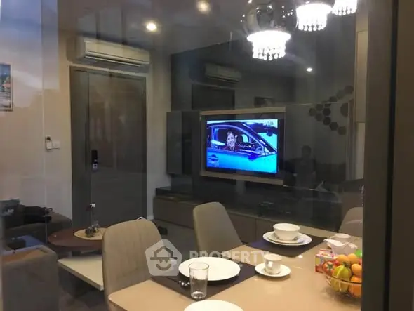 Modern living room with dining area, TV, and elegant lighting