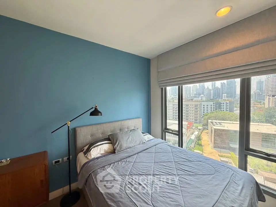 Modern bedroom with city view and stylish blue accent wall