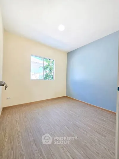 Bright empty room with wooden flooring and large window