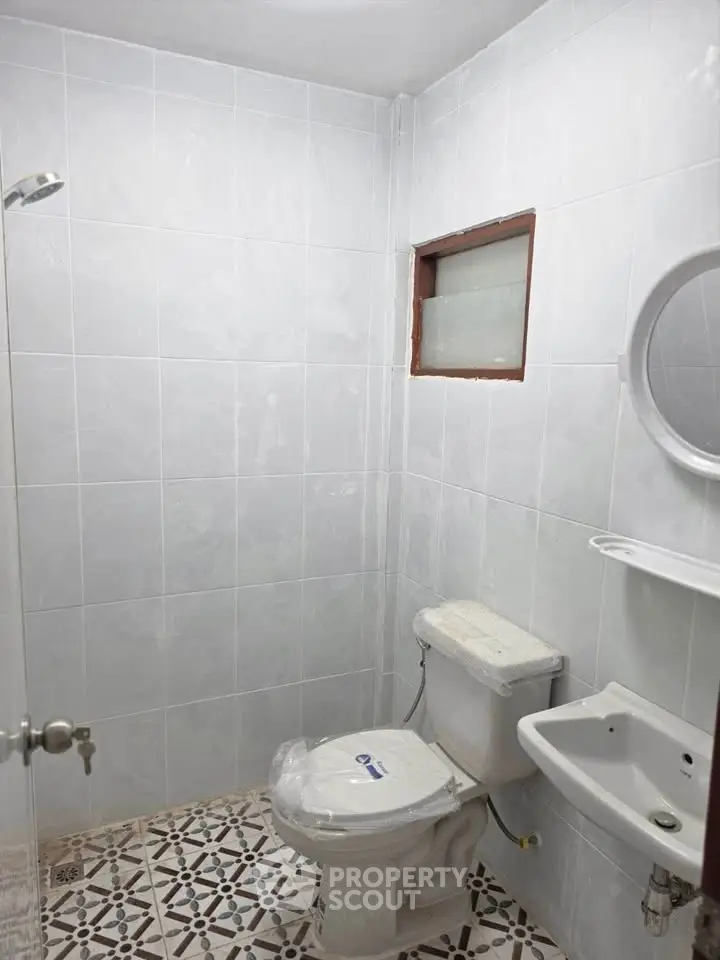 Compact bathroom with white tiles and modern fixtures in real estate property.