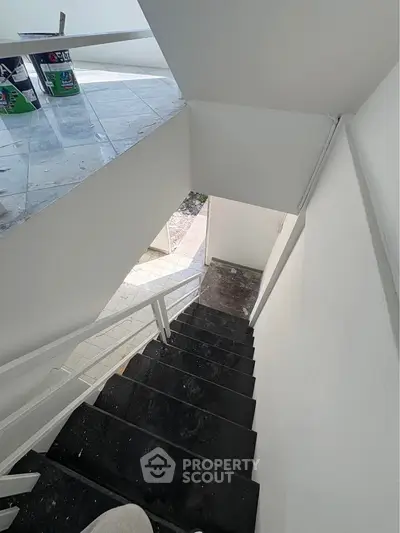 Modern staircase in a residential building with sleek black steps and white walls.