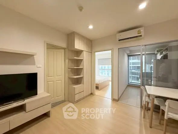 Modern apartment interior with living room, dining area, and view into bedroom, featuring sleek furniture and bright lighting.