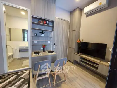 Modern living room with dining area and view into bathroom, featuring sleek furniture and air conditioning.