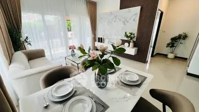 Elegant modern living room with dining area, featuring marble accents and stylish decor.