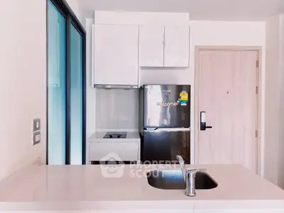 Modern kitchen with sleek white cabinets and stainless steel appliances in a stylish apartment.