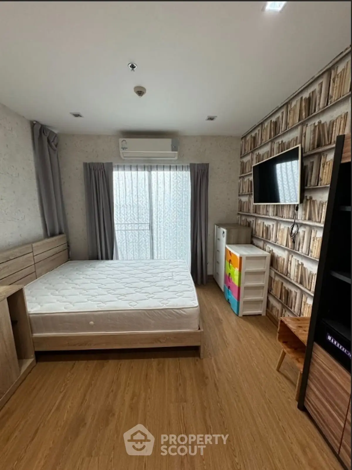 Cozy bedroom with wooden flooring, stylish wallpaper, and modern furnishings.