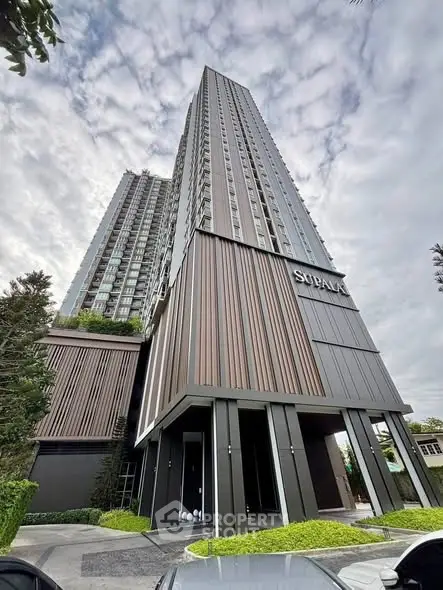 Modern high-rise building with sleek design and lush greenery, perfect for urban living.