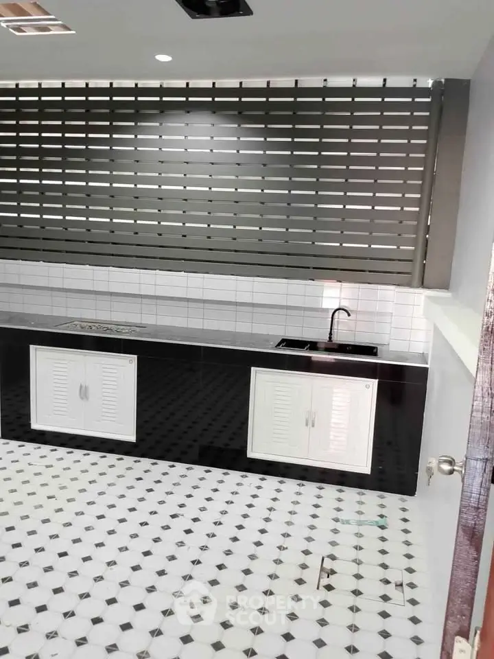 Modern kitchen with sleek black and white design, featuring a spacious countertop and stylish backsplash.