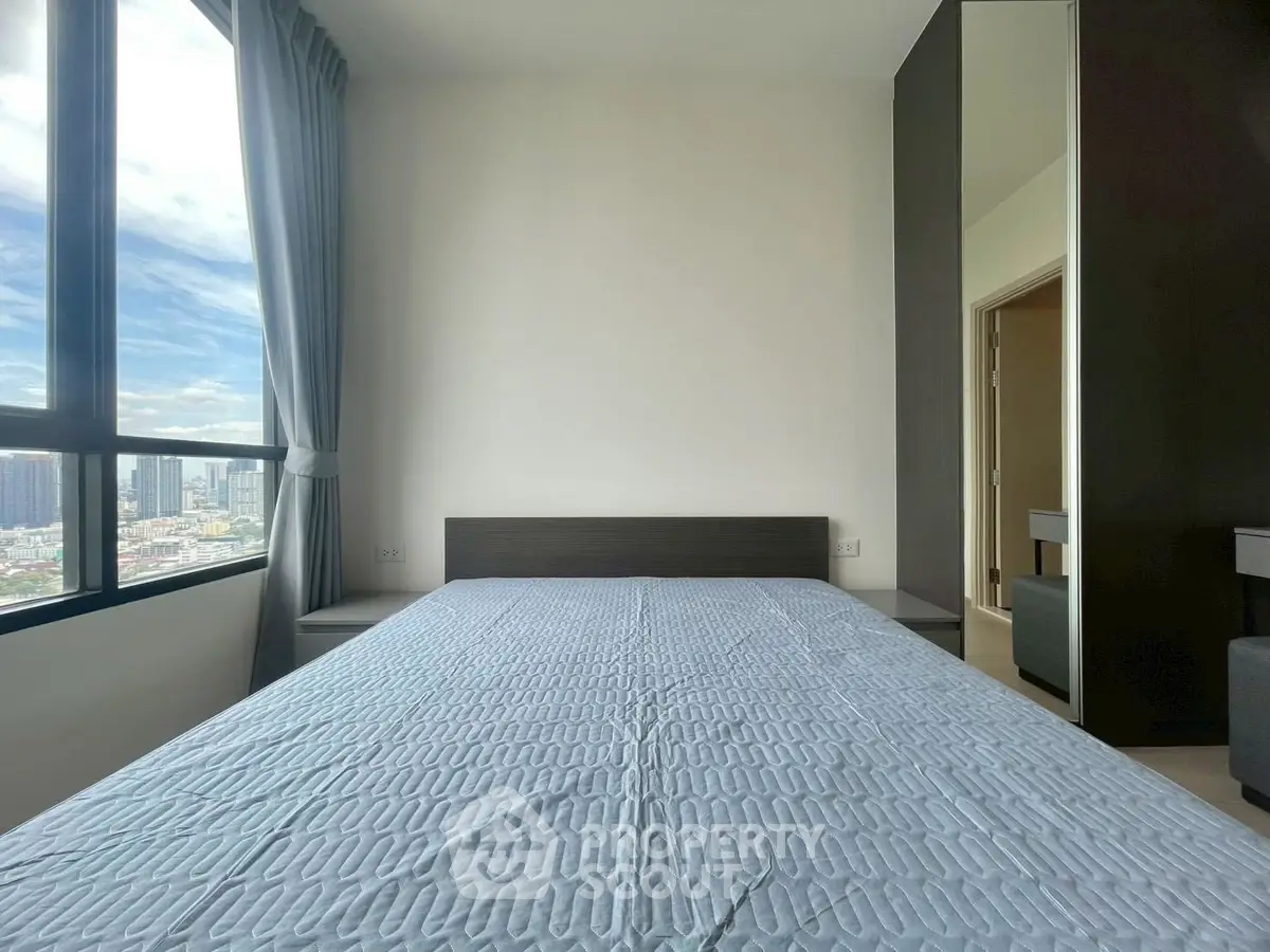 Modern bedroom with large window offering city view, featuring sleek design and ample natural light.