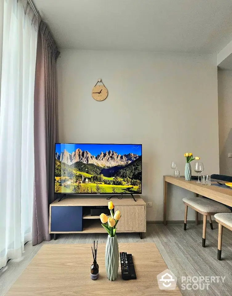 Modern living room with mountain view on TV, stylish decor, and natural light.