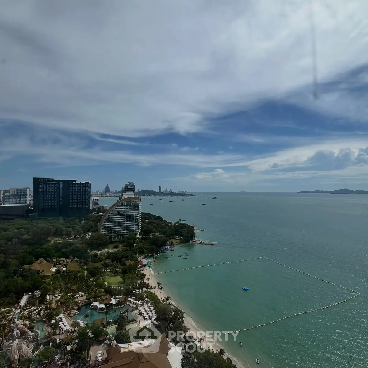 Stunning beachfront view with modern buildings and lush greenery, perfect for luxury living.