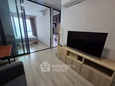 Modern apartment interior with open living room and bedroom, featuring sleek furniture and a washing machine.