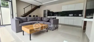 Modern open-layout living room with sleek kitchen and stylish staircase