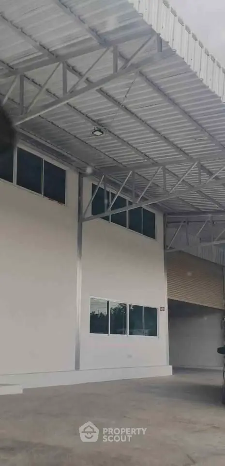 Spacious industrial warehouse exterior with modern design and ample parking space.