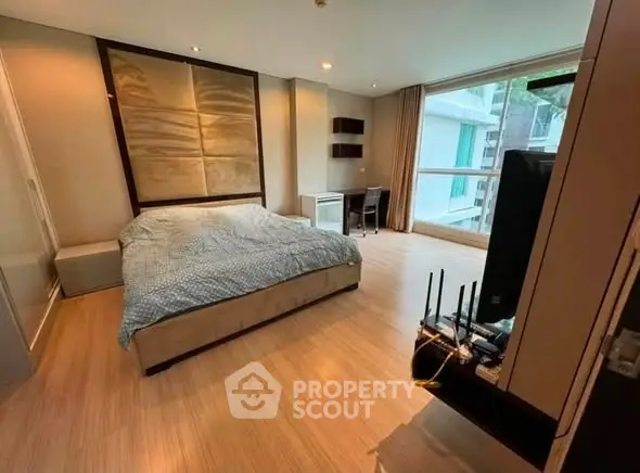 Spacious bedroom with modern decor and large window offering natural light and city view.