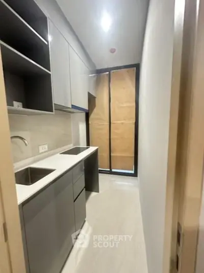 Modern compact kitchen with sleek cabinetry and built-in appliances in a contemporary apartment.