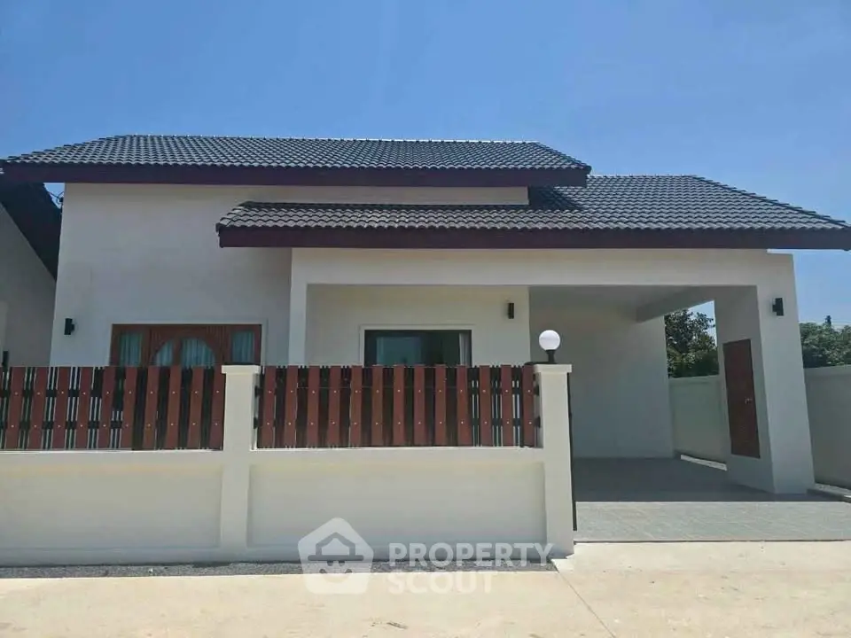 Modern single-story house with sleek design and spacious driveway under clear blue sky.
