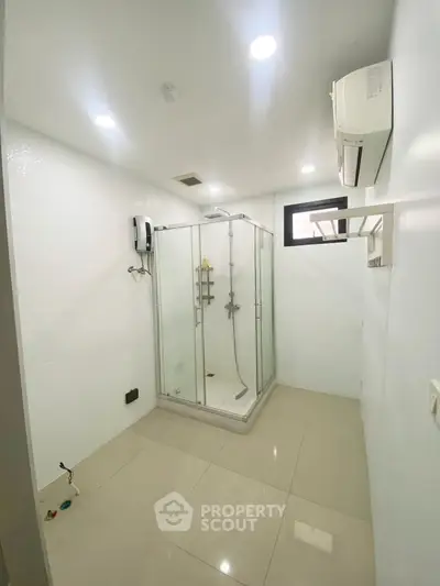 Modern bathroom with glass shower enclosure and air conditioning unit.
