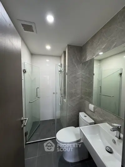 Modern bathroom with glass shower, sleek fixtures, and elegant tile design.