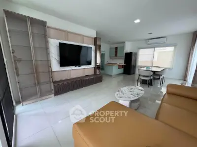 Modern living room with open kitchen, large TV, and stylish furniture in a bright, spacious apartment.