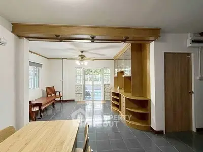 Spacious living room with wooden furniture and large windows for natural light.