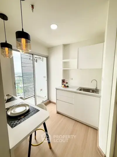 Modern kitchen with sleek white cabinets and balcony view, perfect for urban living.