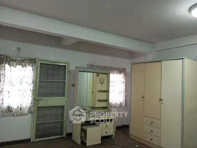 Spacious bedroom with wardrobe and dressing table, natural light through windows, ideal for cozy living.