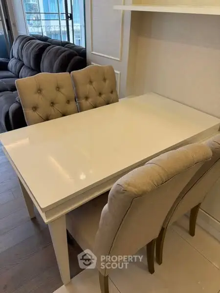 Elegant dining area with plush chairs and sleek white table in modern apartment.