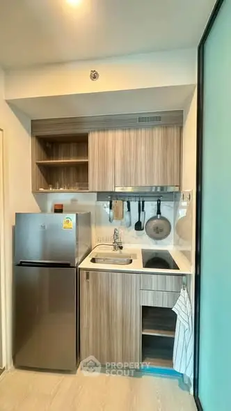 Modern compact kitchen with sleek cabinetry and stainless steel appliances in a stylish apartment.