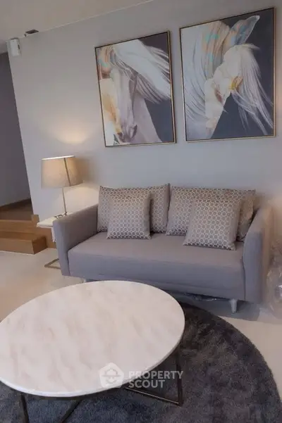 Stylish living room with modern sofa, elegant artwork, and chic marble coffee table.