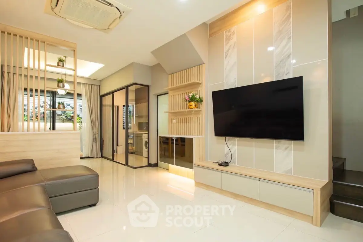 Modern living room with sleek design and large TV, featuring open layout and stylish decor.