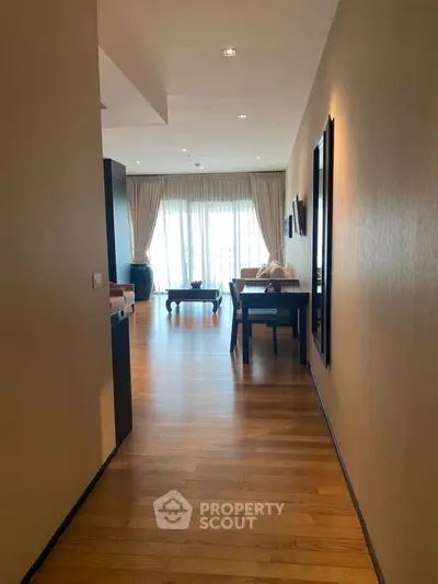 Spacious living room with wooden flooring and large windows offering natural light.