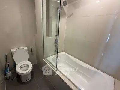 Modern bathroom with sleek bathtub and shower combination in a contemporary apartment.