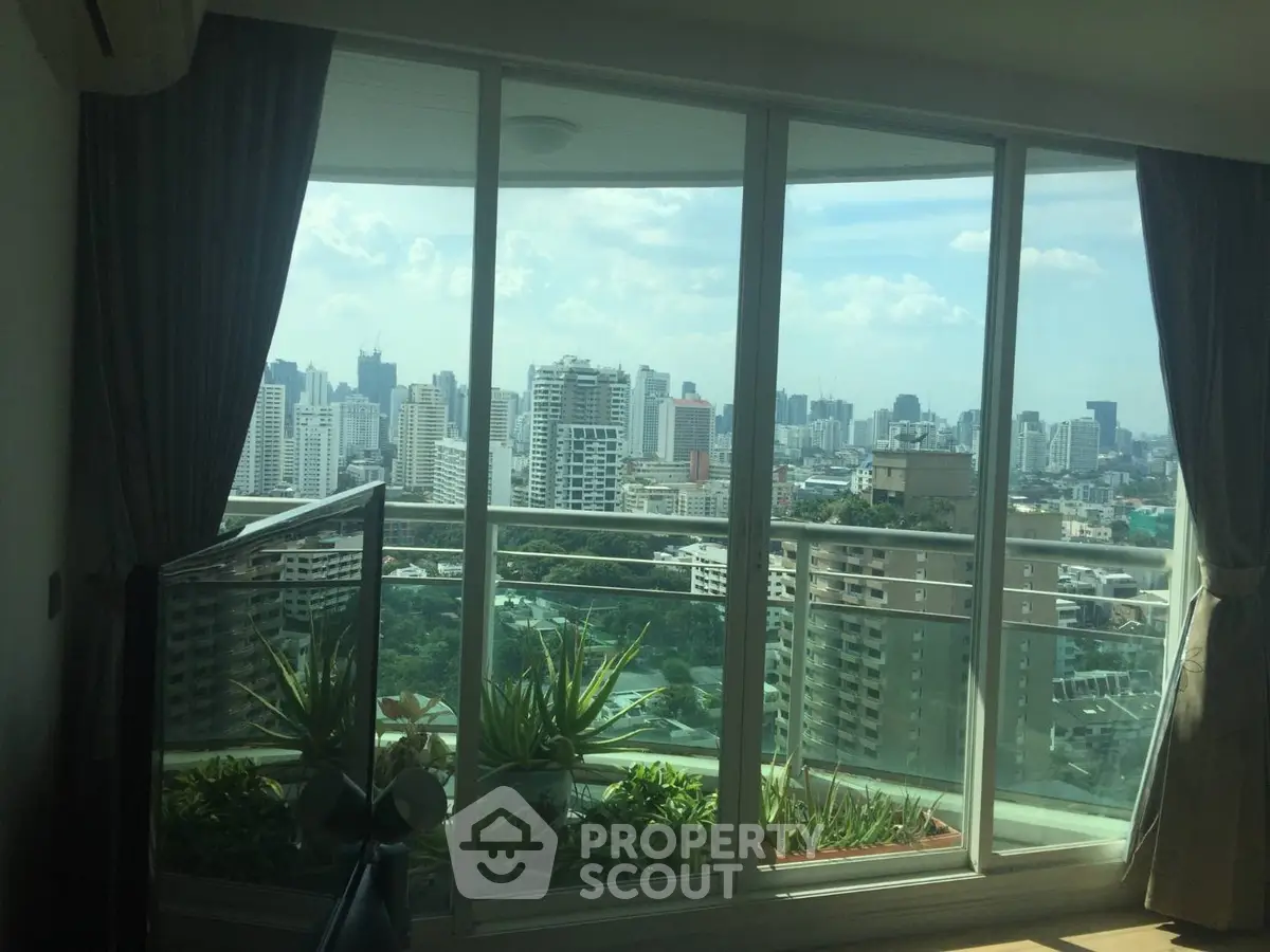 Stunning cityscape view from modern apartment balcony with large glass doors.