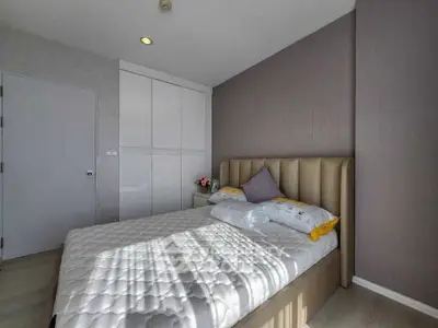Modern bedroom with stylish decor and ample natural light, featuring a comfortable bed and sleek storage solutions.